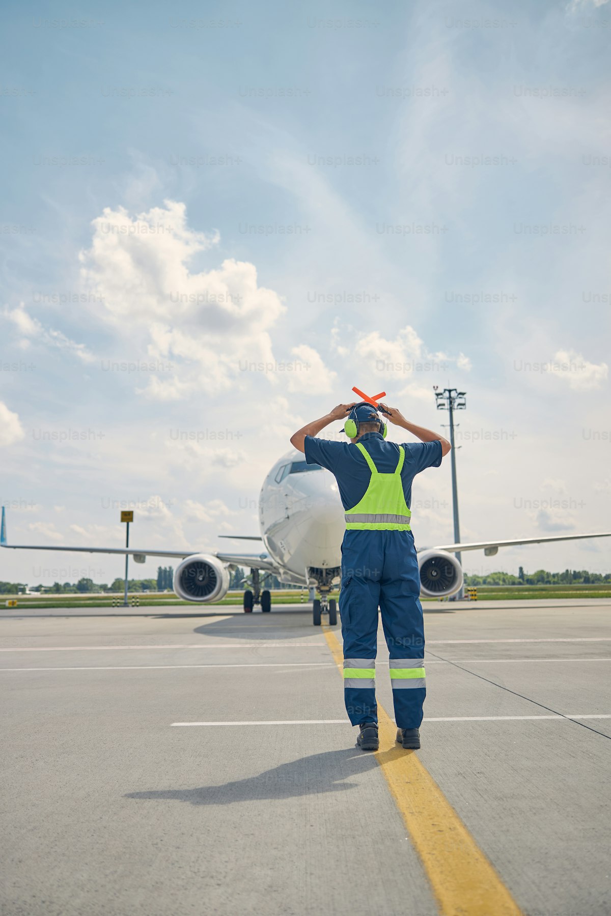 Marshaller mengarahkan pesawat di apron